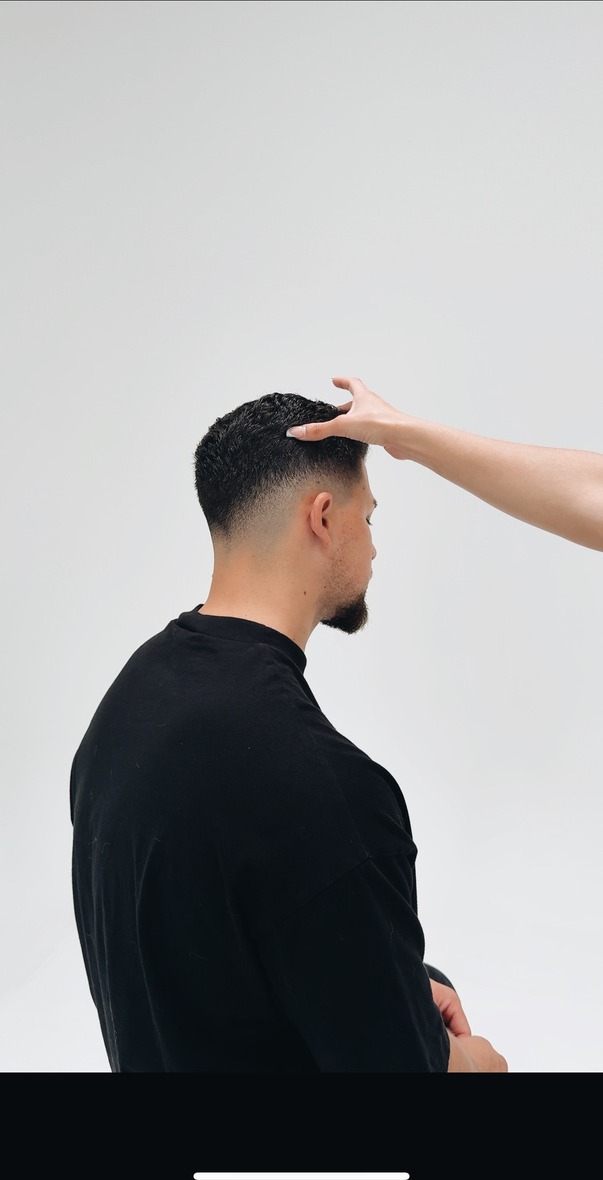 Barber client photographed against a soft grey studio wall