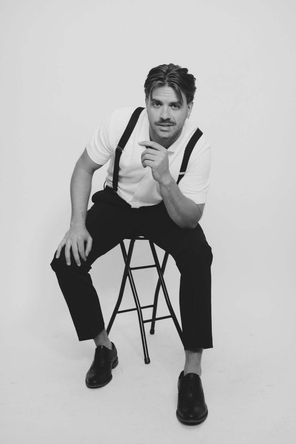 Black and white studio portrait of a man on a stool