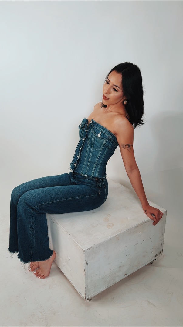 Portrait of a model seated on a concrete plinth in denim