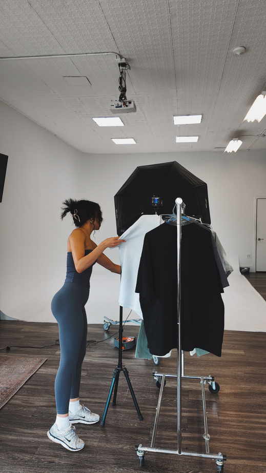 Marissa steaming garments on a rack inside a photography studio