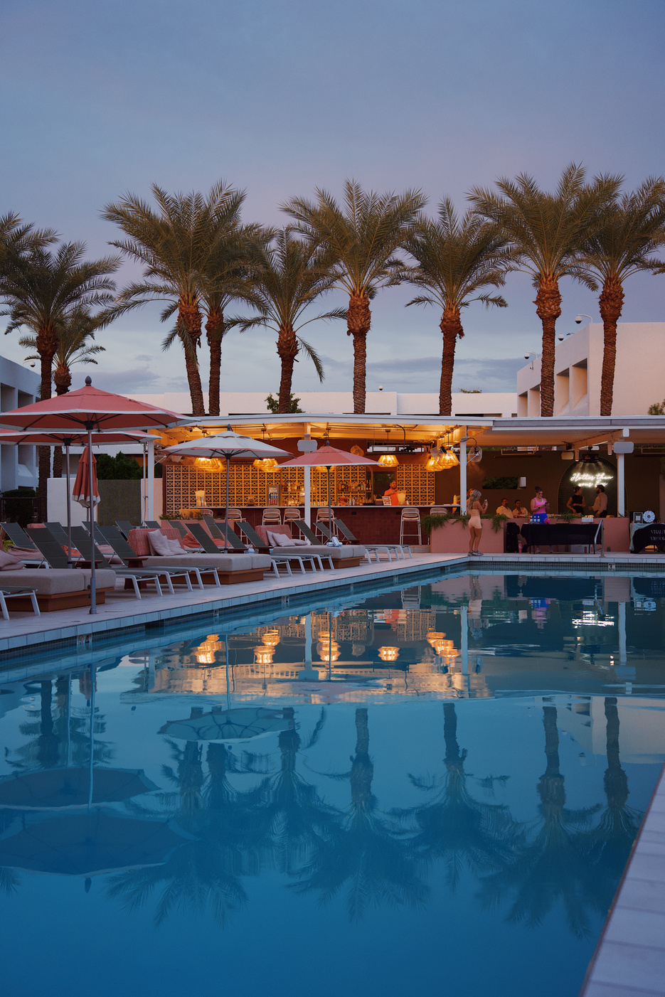 Palm reflections across a resort pool at dusk