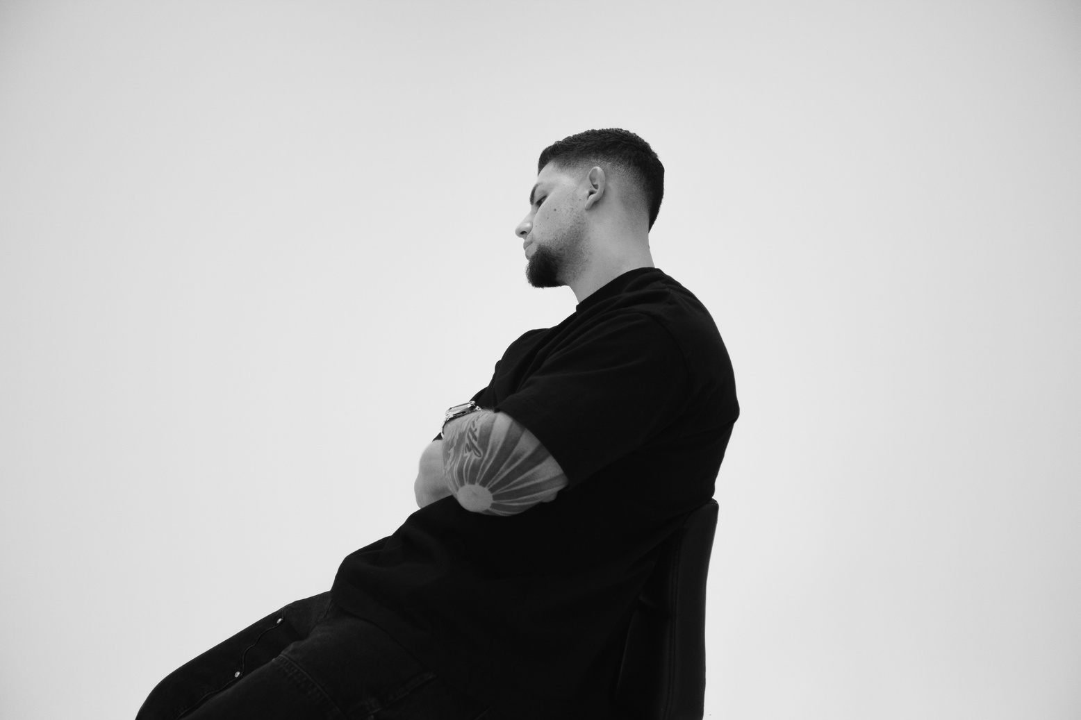 Black and white editorial portrait of a seated man in profile
