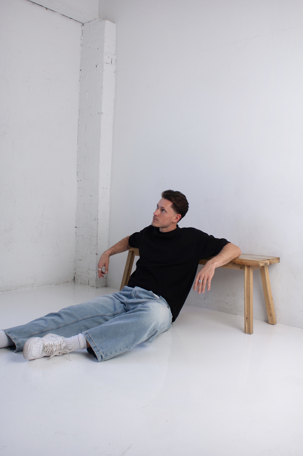 Model seated on a studio floor in denim